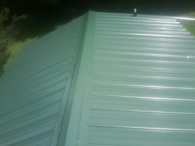 New green metal panels meeting at the ridge of a roof — Flat Roof Repair work by our crew in Maywood