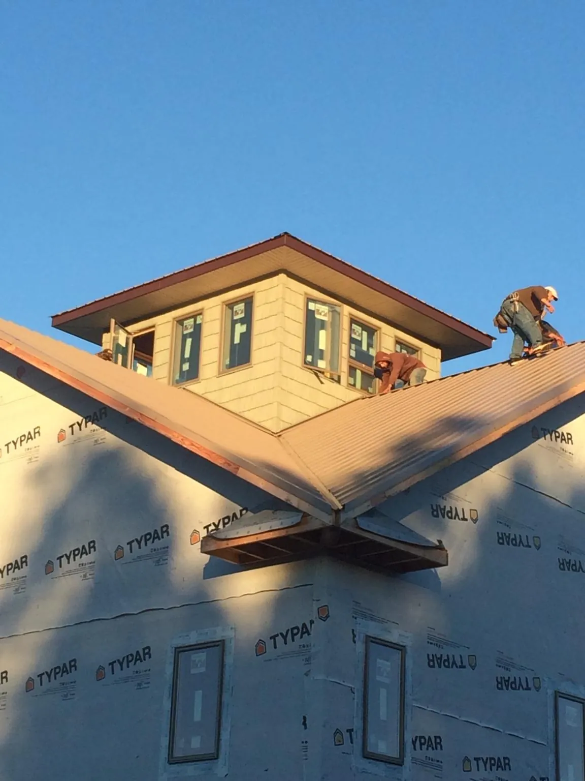 Roofers working around a rooftop cupola on a new metal roof at sunset — Roof Waterproofing in Maywood by Roofing Brothers